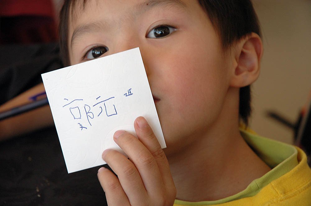 เด็กกำลังแสดงชื่อภาษาจีนที่เขียนด้วยลายมือ